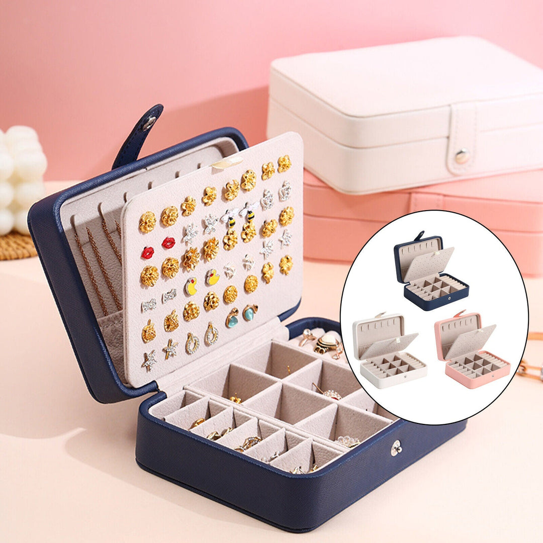 Elegant smykkeskrin i læder med klaplåg, kompakt i blå, rosa, hvid, til stilfuld opbevaring af ringe og øreringe.