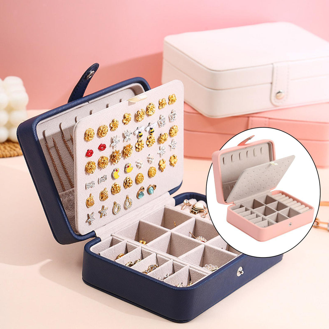 Elegant smykkeskrin i læder med klaplåg, kompakt i blå, rosa, hvid, til stilfuld opbevaring af ringe og øreringe.