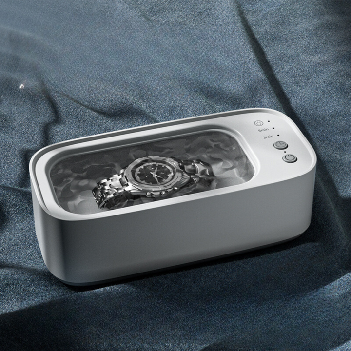 Kompakt ultralydsrenser i blå-gul til effektiv rengøring af smykker, ure og briller.