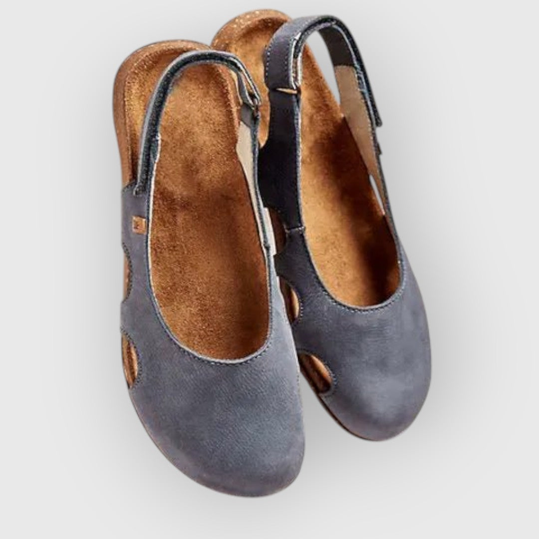 Moderne ortopædiske damesandaler med ergonomisk fodseng og justerbare remme i abrikos på trægulv