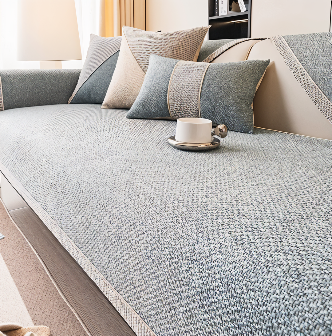 Smukt lysegråt sofabetræk der beskytter møbler og forhindrer glidning.