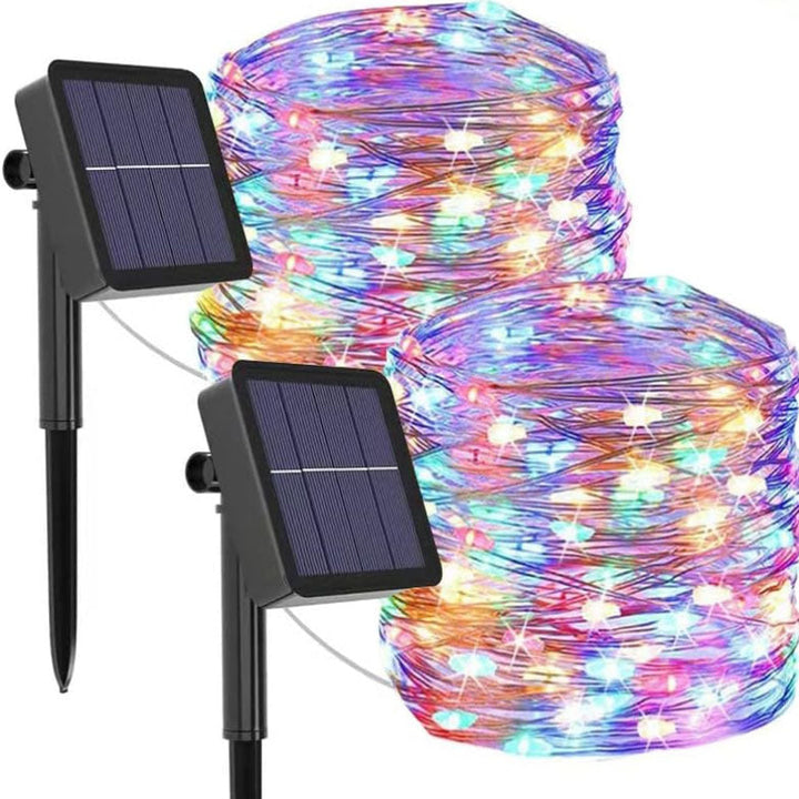 Vandafvisende solcelledrevet lyskæde i haven ved daggry, varme LED-lys, stemningsfuld udendørs belysning