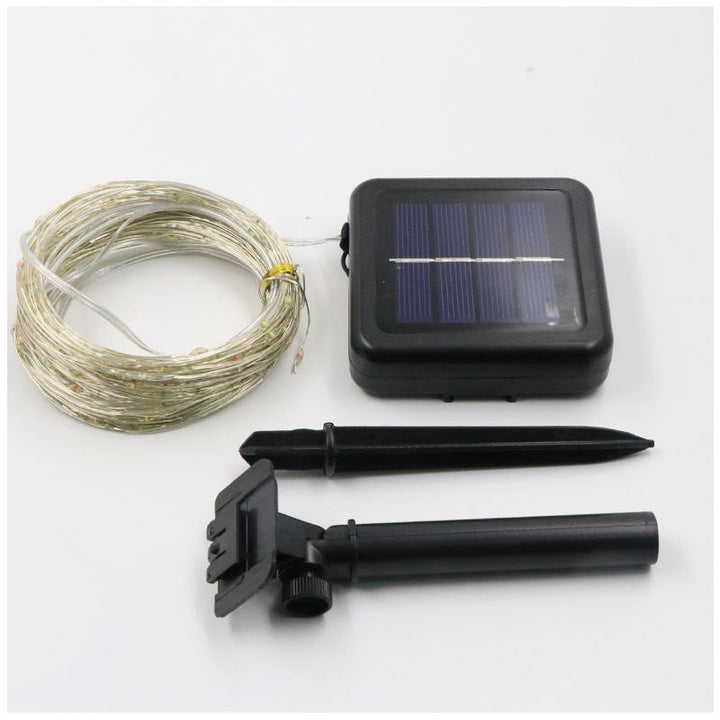 Vandafvisende solcelledrevet lyskæde i haven ved daggry, varme LED-lys, stemningsfuld udendørs belysning