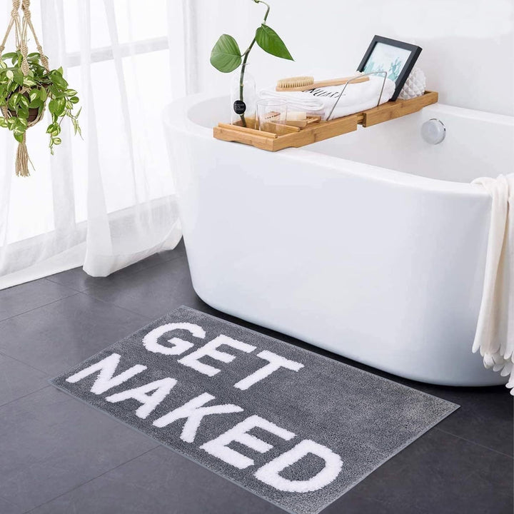 Blød tuftet bademåtte med "Get Naked" tekst i moderne design i et badeværelse, stilfuldt og komfortabelt.