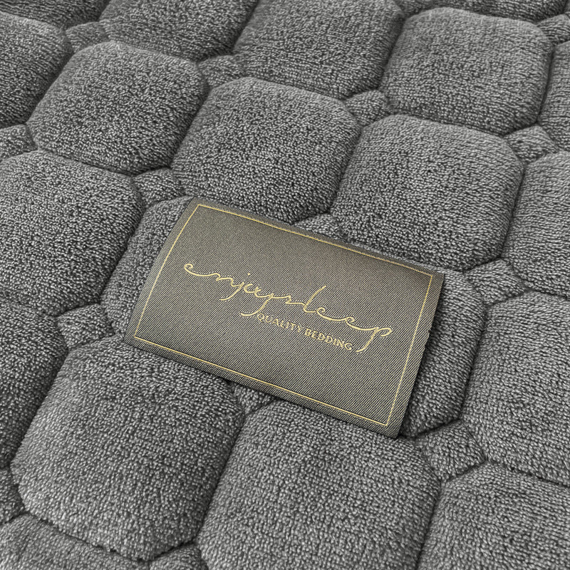 Blødt dagsengetæppe med kvadratisk tekstur, fluffy og moderne, draperet på sofaen for stilfuld hygge.